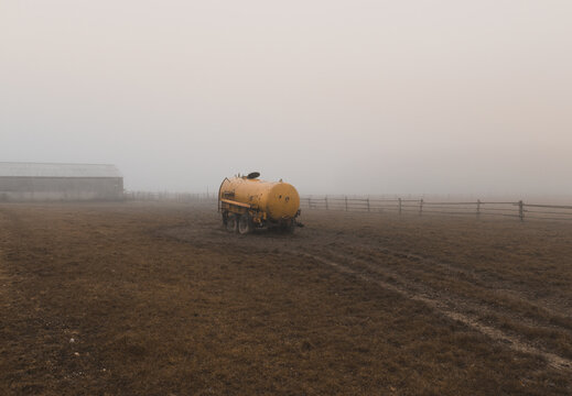 Cow farm building with old yellow tank car in misty fog weather. Colored agriculture photo