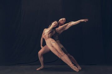 Two flexible dancer, young man and woman in modern art performance isolated on black studio...