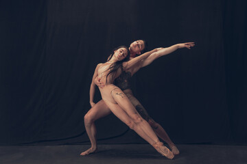 Two flexible dancer, young man and woman in modern art performance isolated on black studio background. Art, motion, inspiration concept.