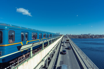 Fototapeta na wymiar The Kiev metro train rides across the bridge over the Dnieper River. Subway bridge over a wide river under a blue sky