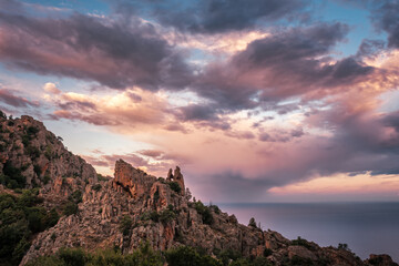 Dramatic morning sky behind the heart shaped hole in the rock of the Calanches, a UNESCO world heritage site in Corsica