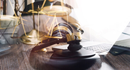 Obraz premium Justice and law concept.Male judge in a courtroom with the gavel, working with, computer and docking keyboard, eyeglasses, on table in morning light