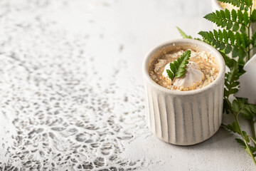 White ceramic cup with hot chocolate decorated with whipped cream, meringue cookies  and green leaf. Winter beverage concept.