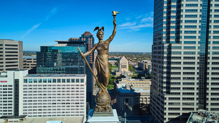 Aerial of Soldiers and Sailors Monument statue at top straight on with Indianapolis downtown in...
