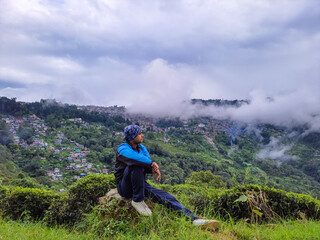 man sitting at mountain top with dramatic sky at morning