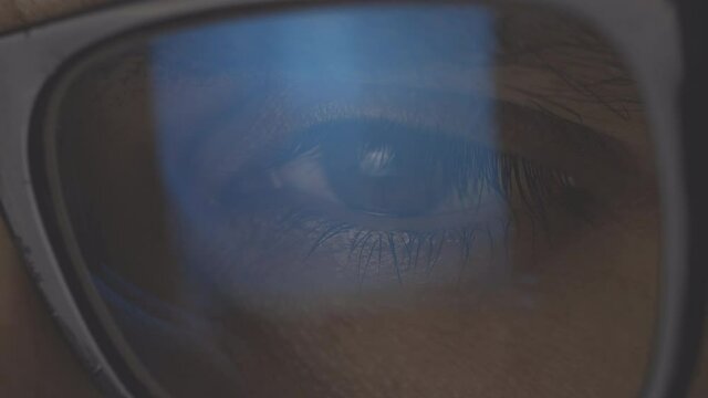 Closeup view of focused businessman wears glasses for reducing eye strain blurred vision looking at pc screen with computer reflection using internet, reading, watching, working online late