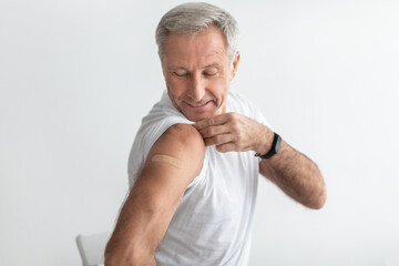 Mature Man Posing After Coronavirus Vaccination Showing Arm, Gray Background - obrazy, fototapety, plakaty