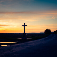 Colorful sunset in autumn in the hungarian countryside with a memorial cross statue