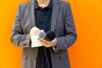 News reporter or broadcast journalist at press conference or media event, holding microphone,...