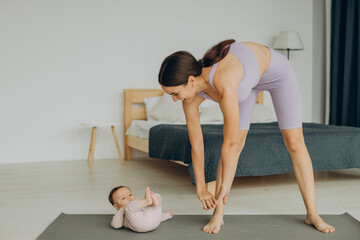 Mother with her baby daughter practice yoga at home