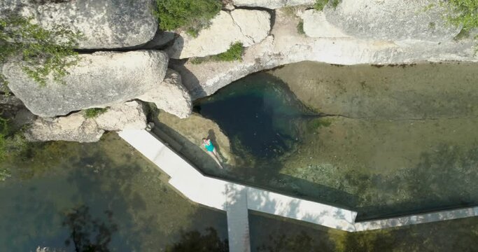 Jacobs Well Natural Spring in Wimberley TX near Austin Texas with Blonde Woman Swimming (Aerial Drone View in 4k)