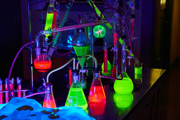 Mad scientist chemistry lab in dark with glowing green and red chemicals