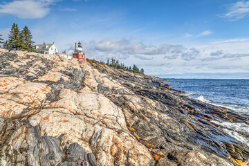 Obraz premium An interesting and beautiful rocky shore rises from the Atlantic Ocean below the historic landmark Pemaquid Point Lighthouse near the Down East community of Bristol, Maine.