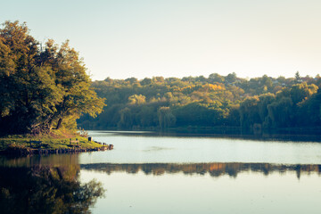 Naklejka na ściany i meble Trees reflecting in the water at the Malomvölgyi-tó in fall, Pécs, Hungary