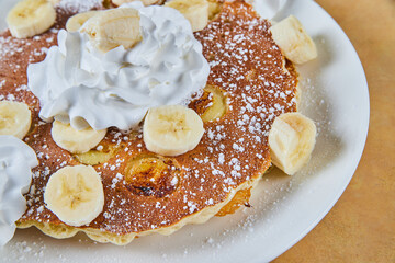 Pancakes with bananas cooked in and whipped cream