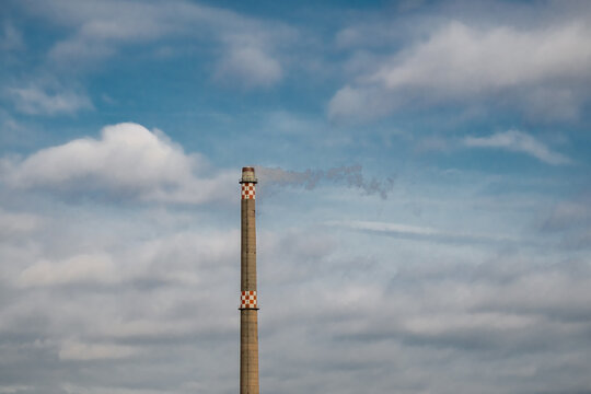 aus einem alten Schornstein dampft der Rauch Richtung Osten mit bew&ouml;lktem blauen Himmel im Hintergrund