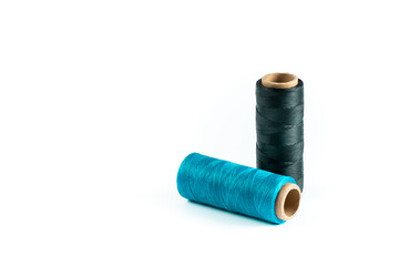 A skein of black and cyan thread. Coils of colored threads on a white background. Waxed sewing thread for leather goods.