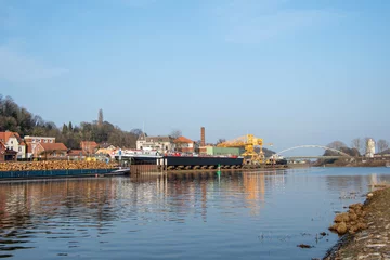 Deurstickers Ein Binnenschiff mit Holzstämmen fährt in Lauenburg in den Elbe-Lübeck-Kanal ein © Dieter
