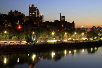 Fototapeta premium Scenic view of beautiful modern buildings, skyscrapers and towers of night big city are reflected in the Dnieper River in evening. Dnipro, Dnepropetrovsk, Ukraine