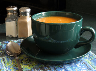 Tomato soup, served in an oversized cup and saucer, on a cool fall day.