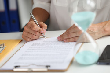 Female hand puts signature in contract at workplace