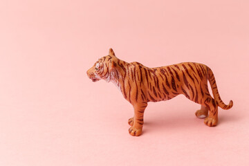 The tiger, symbol of 2022 year. Plastic mini toy figure tiger on a pastel pink background. Copy space. Close-up. New Year's cards