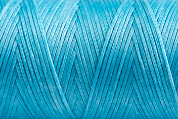 A coil of cyan thread. Spool of colored threads on a white background. Waxed sewing thread for...