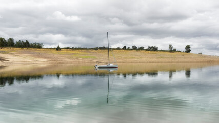 Embarcacion de recreo relejandose en las aguas tranquilas del lago en un dia con nubes
