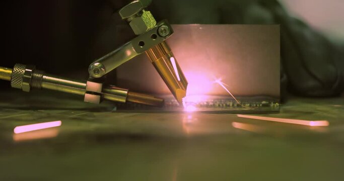 Laser welding machine with hand hold gun. Laser welding is shown in close-up.