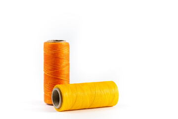 A skein of yellow and orange thread. Coils of colored threads on a white background. Waxed sewing thread for leather goods.