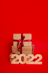 Merry Christmas and Happy New Year. Gift boxes and wooden numerals 2022 on a red background. A place for text.