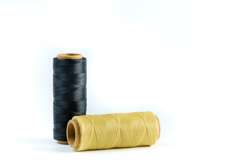 A skein of black and beige thread. Coils of colored threads on a white background. Waxed sewing thread for leather goods.