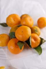 Small tangerines with leaves on a white wooden background