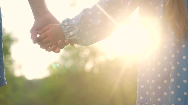 happy family. mom and daughter a hold hands close-up in park. mother and girl kid together hands. parent girl and child happy childhood. happy family sunset in the park. mother day concept