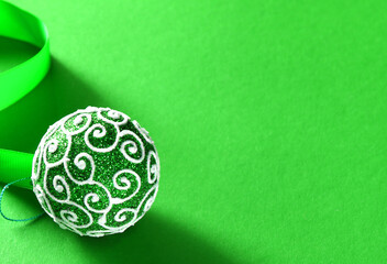 Christmas tree toy. bright green balloon with ribbon on a bright green background. Christmas card in green. Christmas background. Round Christmas tree decoration. High quality photo