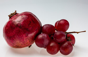 Red pomegranate and bunches of grapes on light background. Still life fruit background.