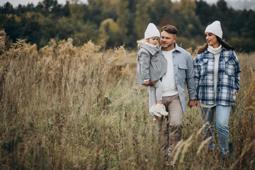 Family with little daughter together in autumnal weather having fun