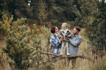 Family with little daughter together in autumnal weather having fun