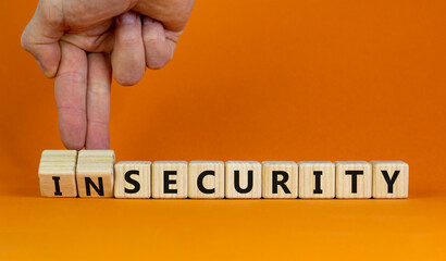 Security or insecurity symbol. Businessman turns wooden cubes, changes words insecurity to security. Beautiful orange background. Business, security or insecurity concept. Copy space.