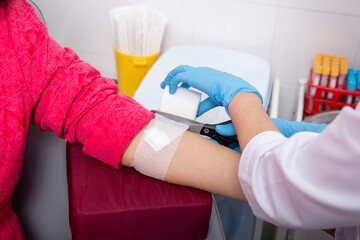 laboratory assistant draws blood from a patient's vein with a disposable syringe. concept is test for covid-19 in medical institution.