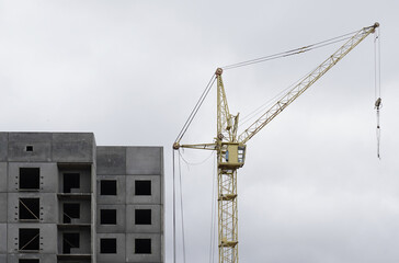 Fototapeta na wymiar There is a crane near a multi-storey building under construction.