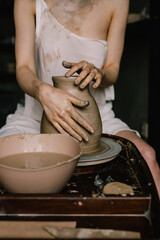 young girl in a white shirt makes a pitcher of clay on a potter's wheel. Pottery workshop of a creative woman. Concept - hobby clay modeling