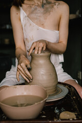 young girl in a white shirt makes a pitcher of clay on a potter's wheel. Pottery workshop of a creative woman. Concept - hobby clay modeling