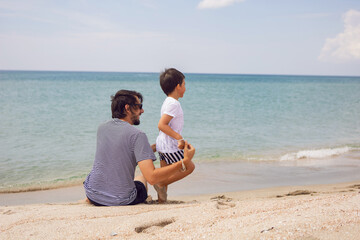 father and son sit on the beach with sand in summer while on vacation