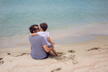 father and son sit on the beach with sand in summer while on vacation