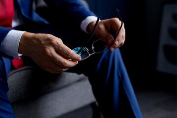 a male consultant in a blue suit holds eyeglasses in his hands. Concept - traditional technologies in business