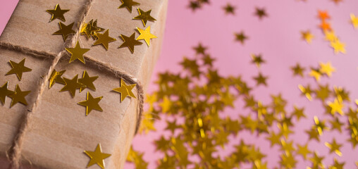 Gift in kravt packaging on a pink background with candy in the form of stars. Baner. Holiday. Birthday. Christmas. March 8