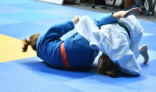 Two Girls judoka in kimono compete on the tatami 