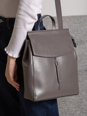 Grey bag backpack with straps with zippers. A bag for things, accessories and textbooks is in the interior of apartment.
