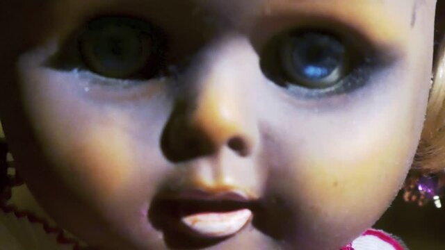The creepy baby doll looks straight into the eyes. Horror movie scene. Evil curse on Halloween.